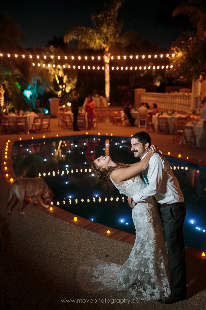 A bride and groom posing for a wedding photo by a swimming pool at a Santa Barbara wedding at a private estate.