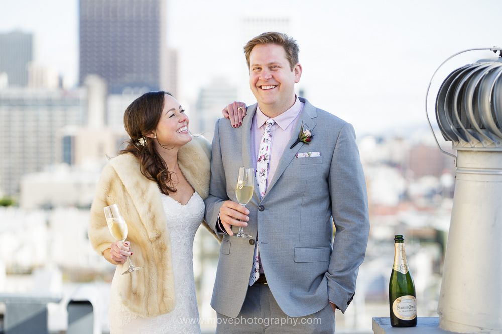 A bride and groom enjoy a glass of champagne on a rooftop in San Francisco's iconic North Beach neighborhood after their San Francisco wedding.